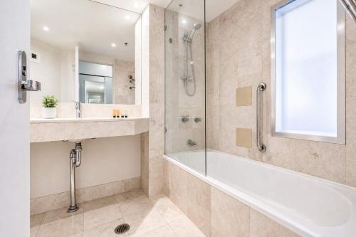 a bathroom with a tub and a sink and a shower at Level 20 King Bed Suite with Ocean Views in Gold Coast