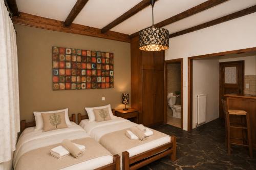 a bedroom with two beds and a chandelier at Goura Guesthouse Lake Doxa Mountain Retreats in Goura