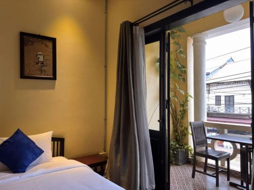a bedroom with a bed and a window and a chair at Inthira Thakhek in Thakhek