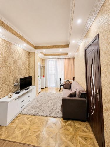 a living room with a couch and a television at Historic Centre Apartment Kutaisi in Kutaisi