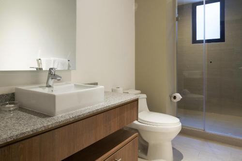 a bathroom with a sink and a toilet and a shower at Suites Metropoli Bristol Parc in Quito
