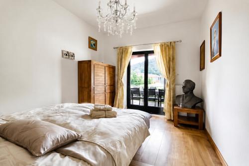a bedroom with a large bed and a chandelier at Villa Noiram - Your dream Getaway in Nature in Senožeče
