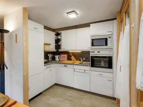 a kitchen with white cabinets and stainless steel appliances at Apartment Chalet l'Aube by Interhome in Vers L'Eglise