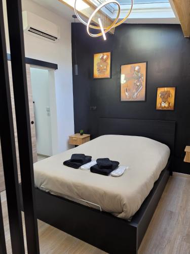 a bedroom with a bed with black walls and a chandelier at Le Baiser Doré in Sainte-Marie-aux-Chênes