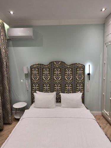 a bedroom with a large white bed with a black headboard at Njala Residence in Stantsiya Tekeli