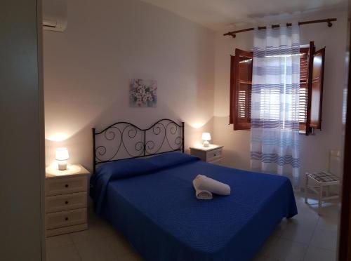 a bedroom with a blue bed with a hat on it at Casa Nespolo in San Vito lo Capo