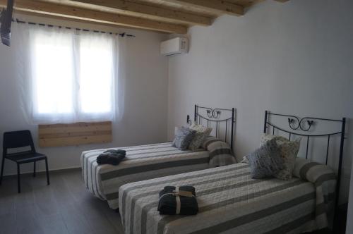 a room with two beds and a chair and a window at Casa Rural El Capricho in Casas del Monte