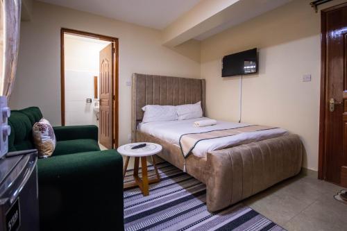 a bedroom with a bed and a couch and a tv at Caramel Studio In CBD with Free WI-FI in Nanyuki