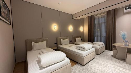 a hotel room with two beds and a table at Maskan Premium Hotel Tashkent in Aktepa-Chigatay