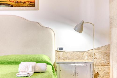 a bedroom with a green bed and a lamp at Masseria Prisuti in Punta Prosciutto