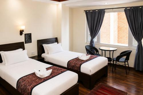 a hotel room with two beds and a table at Apartment Hotel 11 Thamel in Kathmandu