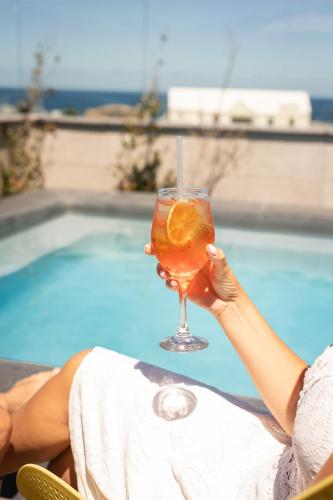 a woman holding a drink in front of a pool at Hermanus Waterfront Apartments in Hermanus