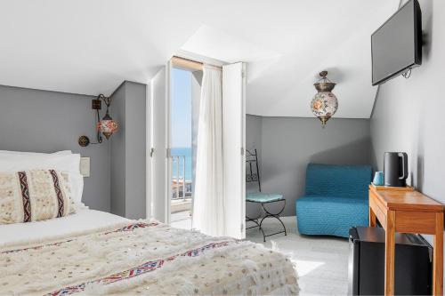 a bedroom with a bed and a television and a chair at Casa da Praça - Alojamento Local in Sesimbra