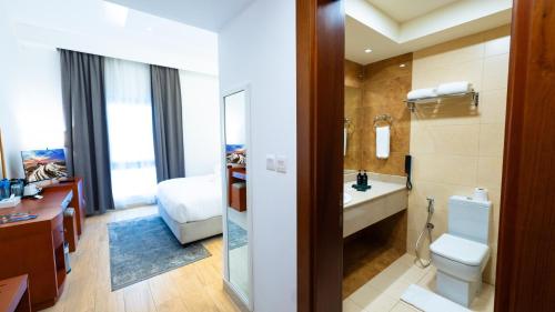 a bathroom with a toilet and a sink and a bed at Premium Four Star Hotel by Blue Collection in Ras al Khaimah