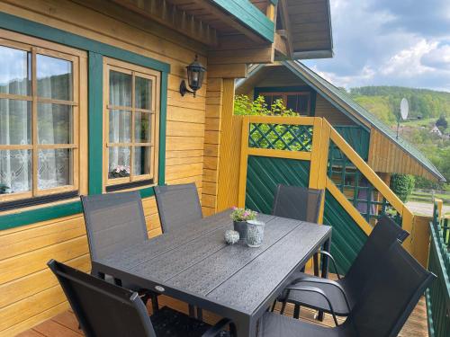 a wooden deck with a table and chairs on a house at Der Fuchsbau - 3 separate Blockhäuser - ruhige Lage - 50m bis zum Wald - eingezäunter Garten in Bad Sachsa