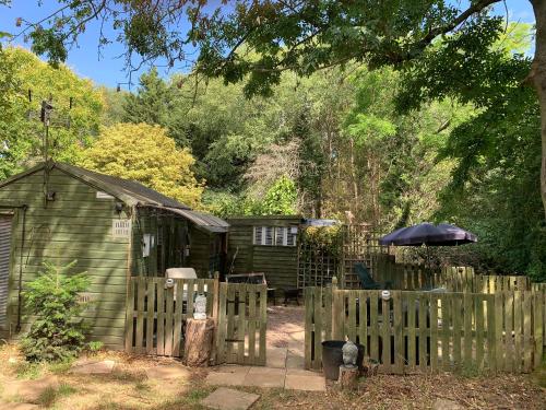 a wooden fence with an umbrella next to a shed at Hedgehog Lodge in Colwall