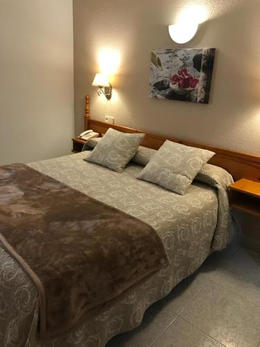 a bedroom with a large bed with two pillows at Hostal Alcázar in Toledo
