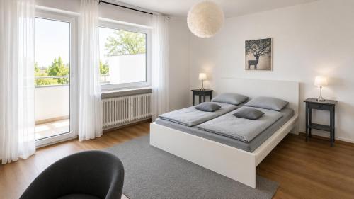 a white bedroom with a bed and two windows at Pulheim Living 3 in Pulheim