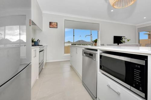 a kitchen with white appliances and a large window at Hunter Valley Bercuti in North Rothbury