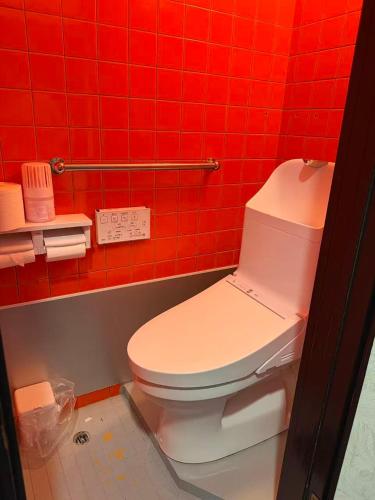 a bathroom with a toilet in a red tiled wall at 島の宿 in Toba