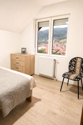 a bedroom with a bed and a chair and a window at Apartmani Resimic in Ivanjica