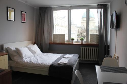une petite chambre avec un lit et une fenêtre dans l'établissement Noctis Apartment Nowogrodzka, à Varsovie