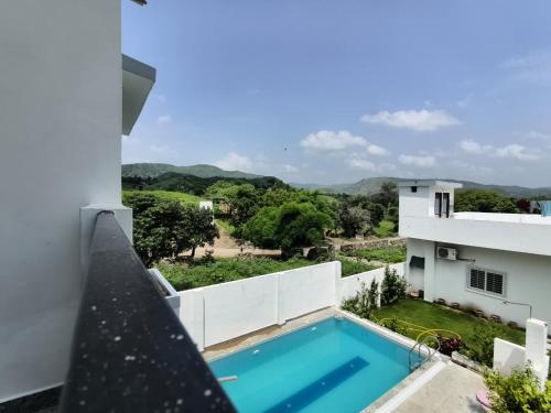 a view from the balcony of a house with a swimming pool at Rayta Aravalli View Villa in Udaipur