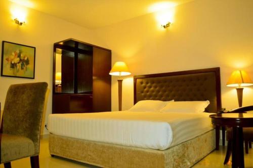 a hotel room with a large bed and a chair at Hotel Aristos Boutique & Suites in Chittagong