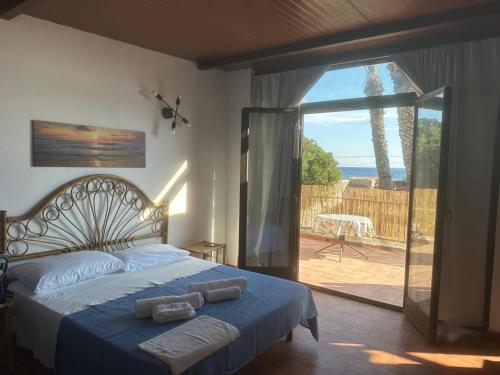 a bedroom with a bed and a sliding glass door at Il Villaggetto sul Mare in Favignana