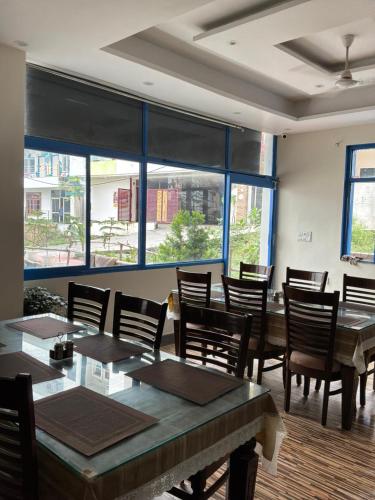 a dining room with tables and chairs and large windows at Moonshiva stay and cafe in Rishīkesh