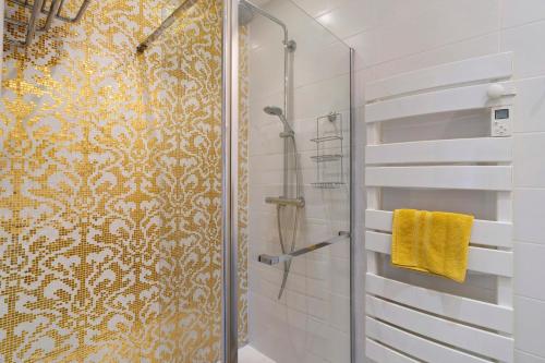 a bathroom with a shower with a yellow patterned wall at La Table De Pierre - Chambre d'Hôte in Lussas-et-Nontronneau