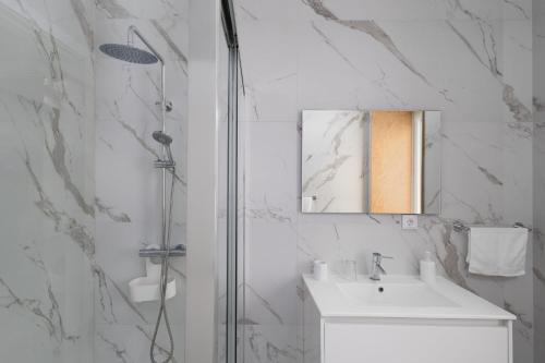 a white bathroom with a sink and a shower at Casa da eira in Ribeira Grande