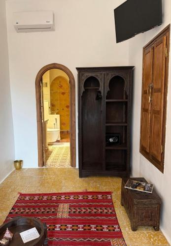 a living room with a tv and a room with a rug at Riad los simbolos in Tétouan