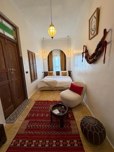 a bedroom with a bed and a chair and a table at Riad los simbolos in Tétouan