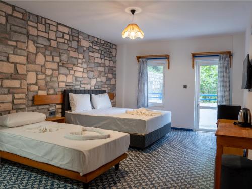 two beds in a room with a stone wall at Karma homes in Turunç
