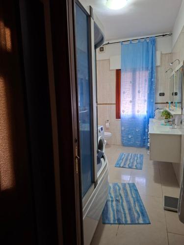 a bathroom with a shower and a toilet and blue rugs at stanza a casa marina in Rosolina