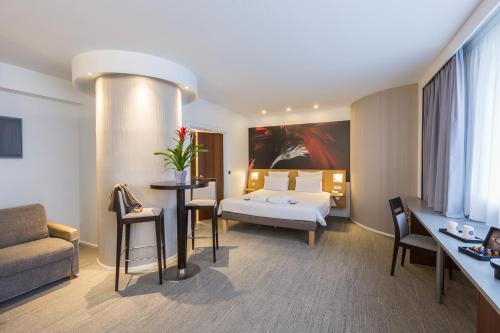 a hotel room with a bed and a couch and a table at Novotel Poitiers Site du Futuroscope in Chasseneuil-du-Poitou