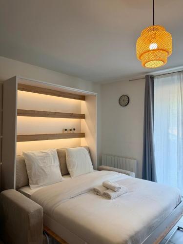 a bedroom with a large bed with white sheets at Le Marronnier - Studio confortable proche de Lyon in Charbonnières-les-Bains