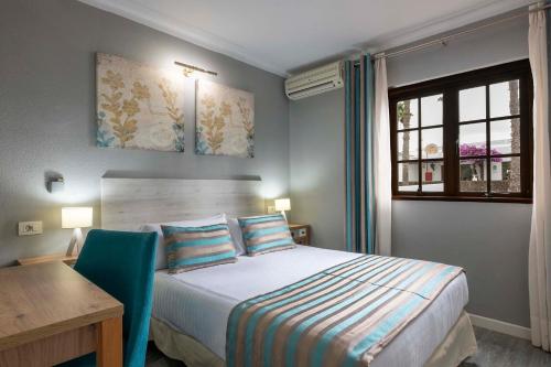 a bedroom with a bed and a desk and a window at Ona Las Brisas in Playa Blanca