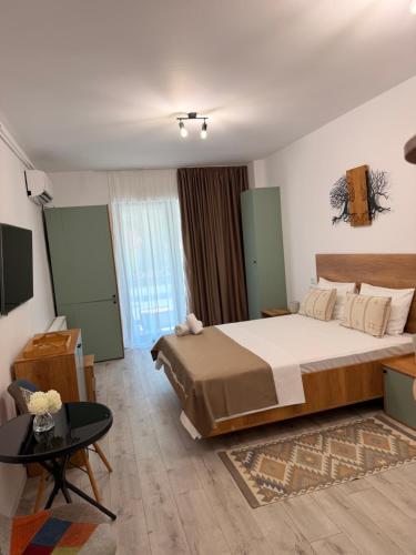 a bedroom with a large bed and a table at Apartament Căciulata Duo cu 2 camere independente in Căciulata
