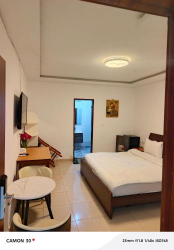 a bedroom with a bed and a table and a tv at Hotel Nana in Abidjan