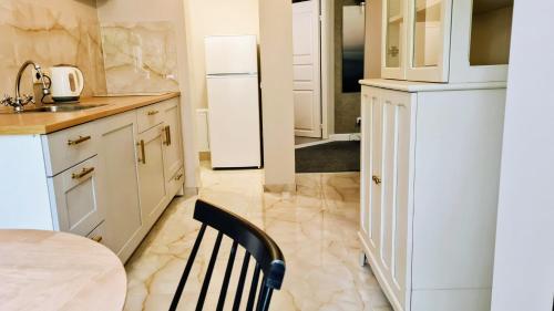 a white kitchen with a table and a refrigerator at Teodor Apartment in Budraičiai