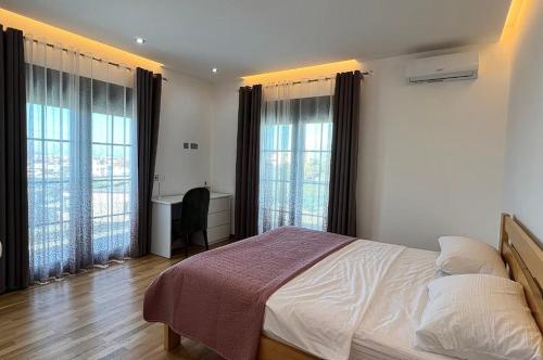a bedroom with a bed and two large windows at Located in a quiet area ! in Durrës