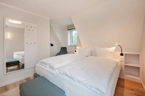a bedroom with a large white bed and a mirror at Fischerdorf DDH Hafftraum in Zirchow