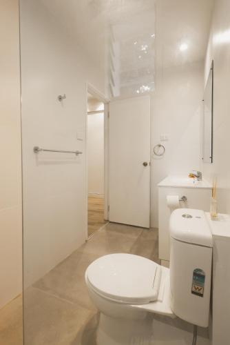 a white bathroom with a toilet and a sink at Suva Point Ocean Front Nukulau Island Views in Suva