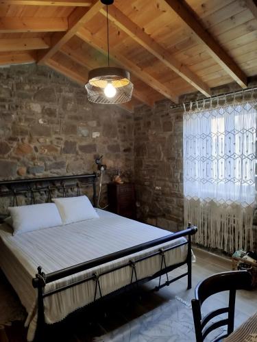 a bed in a room with a stone wall at Lilly of Lemnos in Roussopoúlion