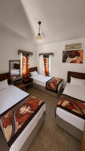 a hotel room with three beds and a television at CİELO Otel in Bodrum City