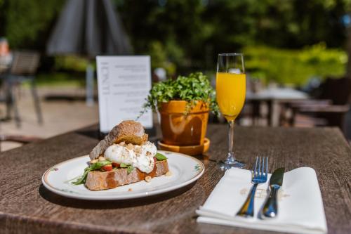 a table with a plate of food and a glass of orange juice at Stadspaleis Hotel & Restaurant OldRuitenborgh in Vollenhove