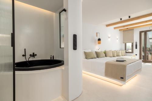 a white bathroom with a sink and a bed at The Lofts Paros Executive Suites in Naousa