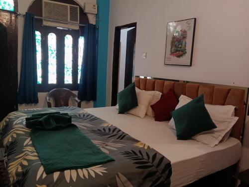 a bedroom with a bed with green and red pillows at Sandhya Guest House Varanasi Near Ganga River in Varanasi